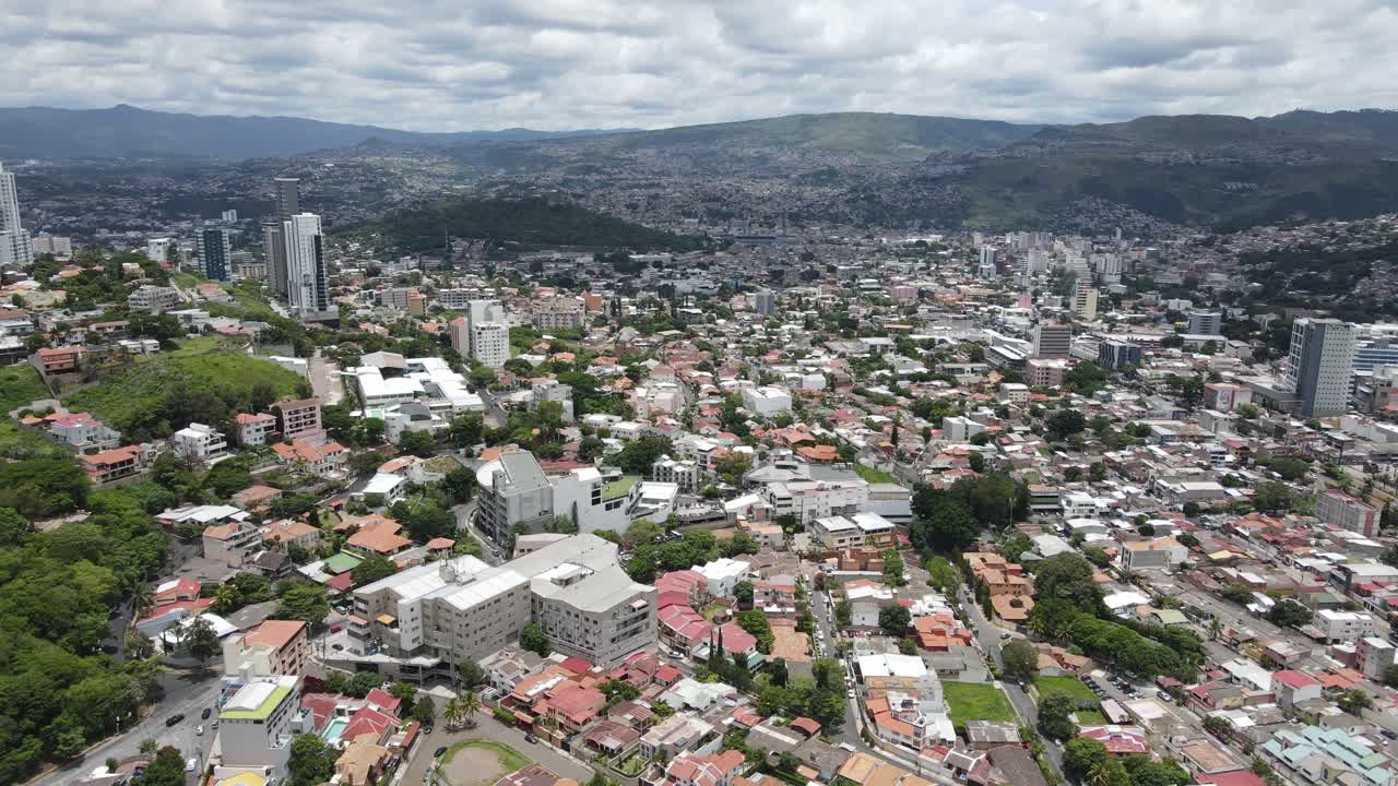 Vista aerea con drone di Tegucigalpa, Honduras, sullo skyline del Distrito Central con distretti urbani densi, torri, strade e colline circostanti sotto un cielo nuvoloso