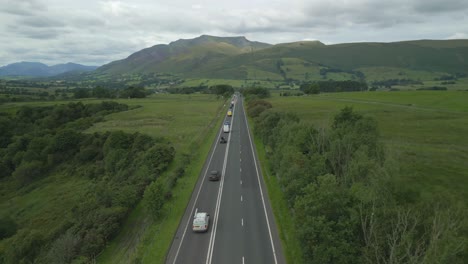 Folgen-Sie-Dem-Verkehr-Entlang-Der-Stark-Befahrenen-Landstraße-A66-Mit-Langsamem-Anstieg-Und-Zeigen-Sie-Den-Berg-Blencathra-An-Einem-Bewölkten-Sommertag