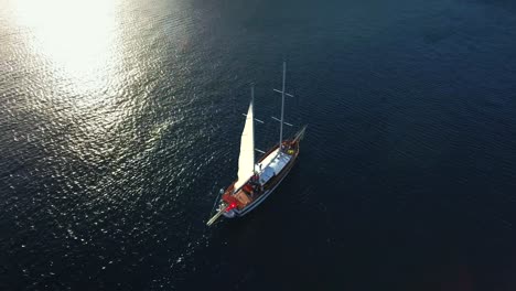 aerial shot of sailing boat in blue sea at sunset