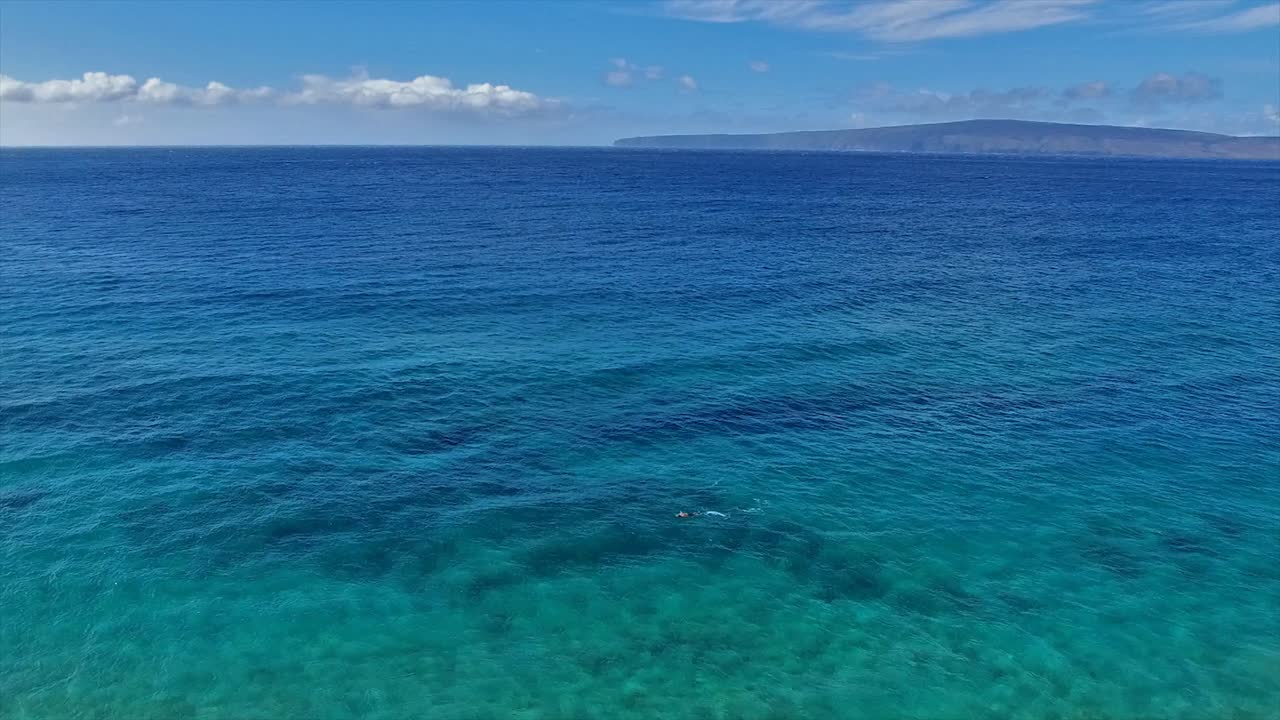 아름다운 푸른 물 속에서 하와이 마우이에서 스노클러의 패닝 공중 샷