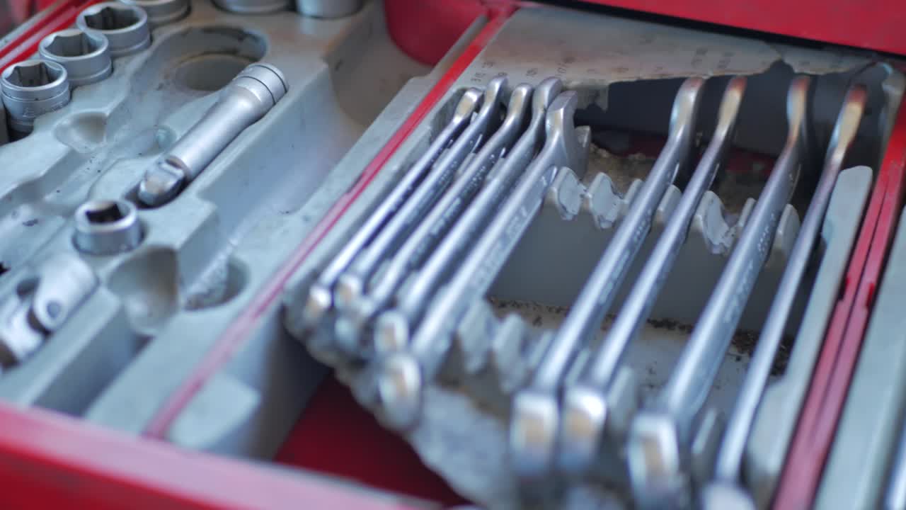 A close up panning of wrenchs and screwdrivers from a drawer of a toolbox
