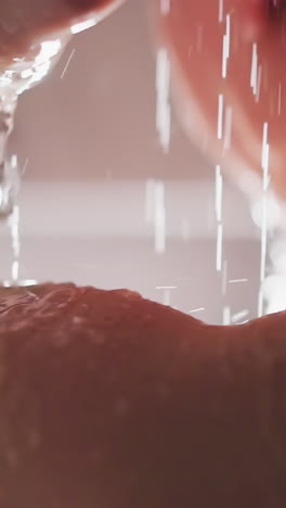 la señora se ducha cuidadosamente lavando el cuerpo. la mujer lava el cuerpo y el cabello bajo agua caliente en la ducha. las gotas de agua caen sobre el cuerpo de la mujer joven