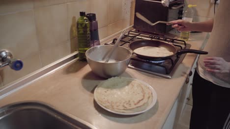 la mujer está girando un panqueque a otro lado en la cocina en la estufa girando a la derecha