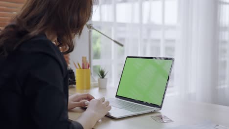 green screen footage of a laptop with an asian woman sitting with her back.