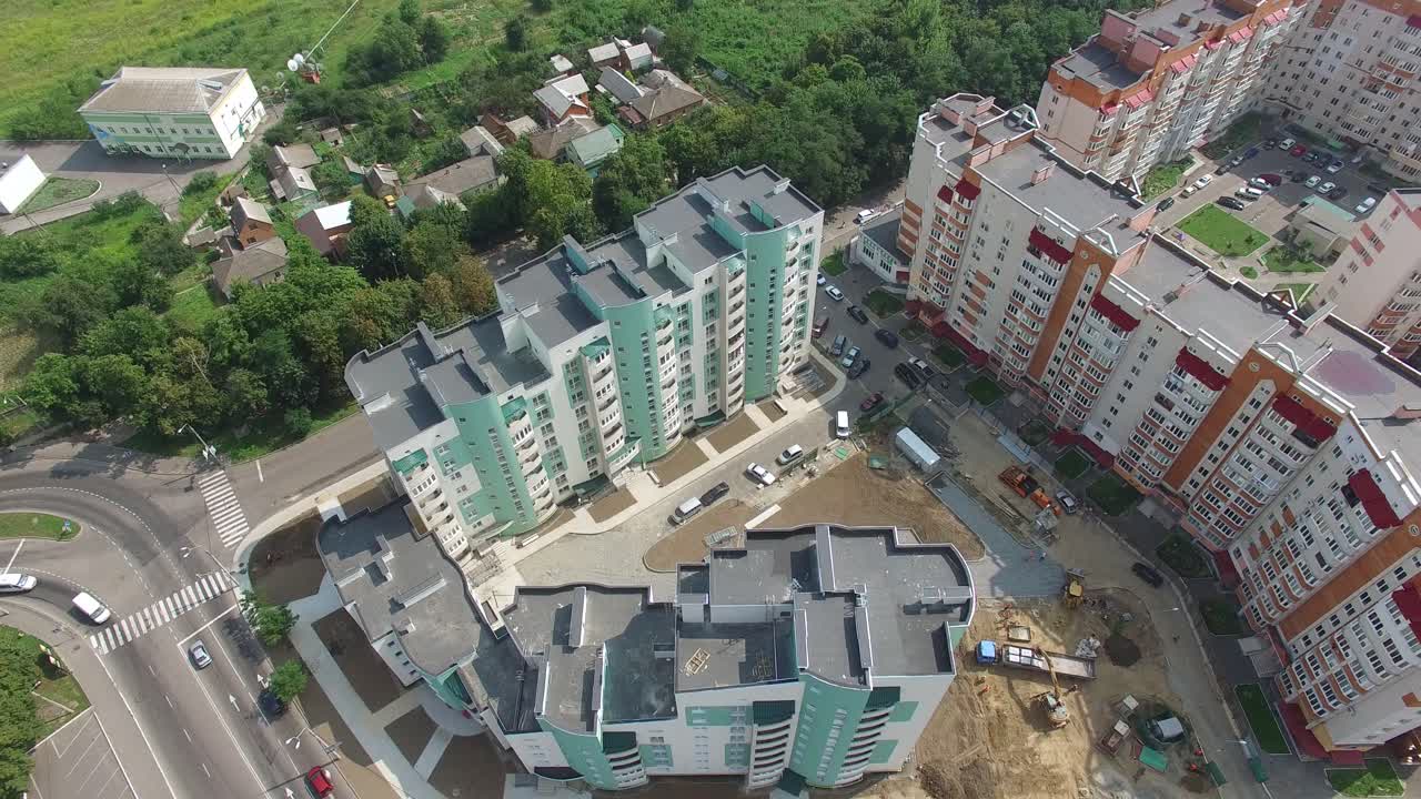 Flying over the modern residential buildings and green trees in the town. New houses with residential apartments. Aerial view