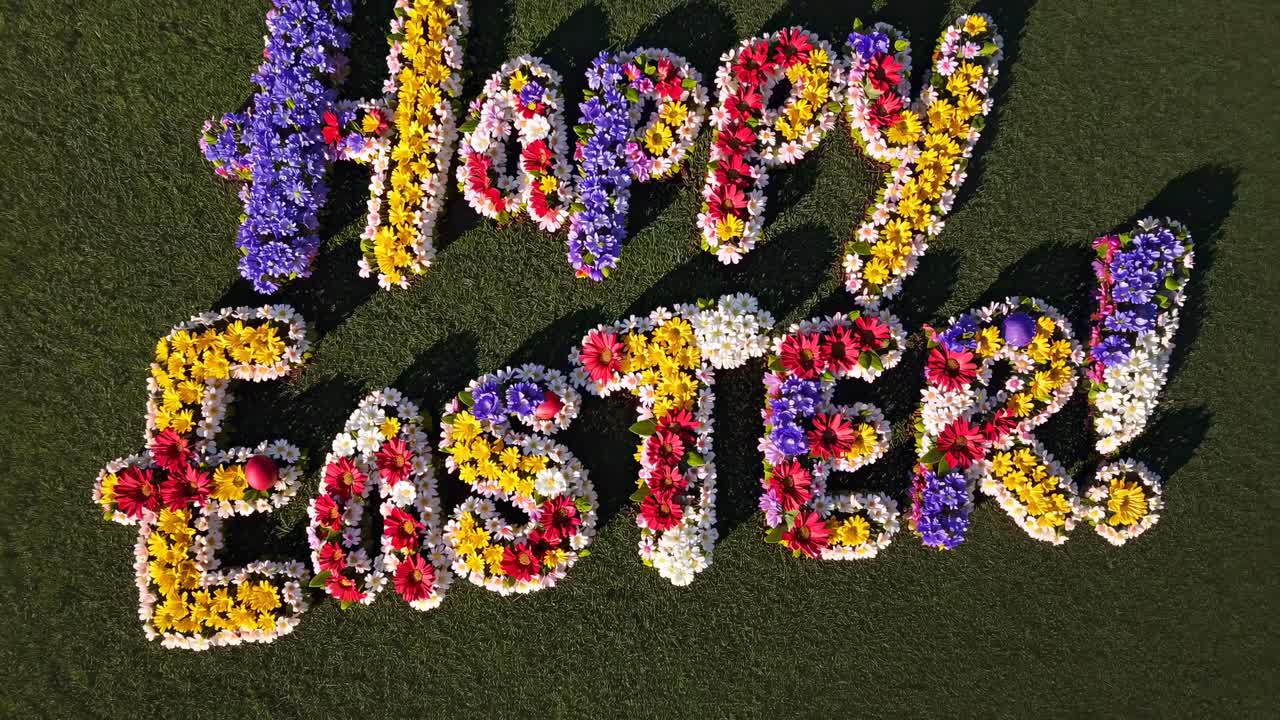 Aerial view of 'Happy Easter!' spelled with colorful flowers on grass