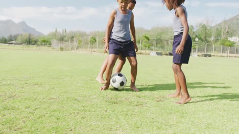 Video-Von-Drei-Glücklichen-Afroamerikanischen-Schulkindern,-Die-Barfuß-Auf-Dem-Feld-Fußball-Spielen