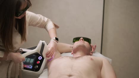 a man undergoing a laser hair removal treatment on his chest with a professional technician in a clinic