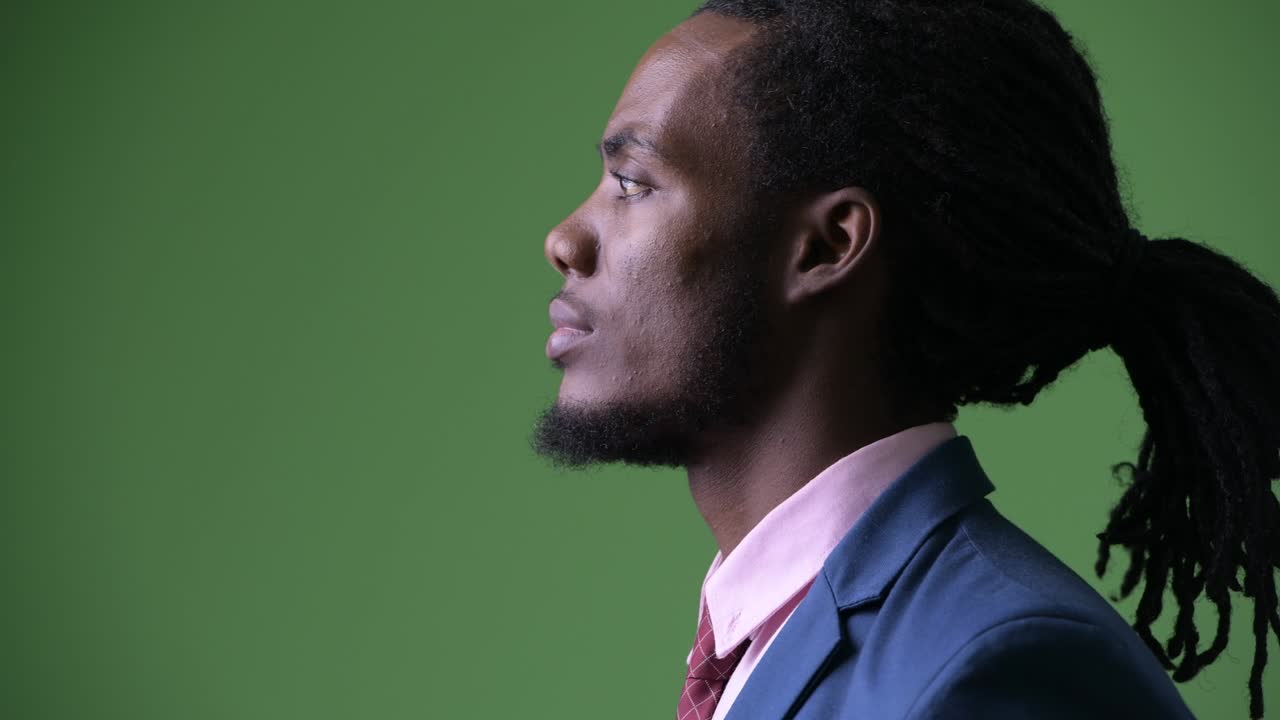 joven empresario africano guapo con dreadlocks contra un fondo verde