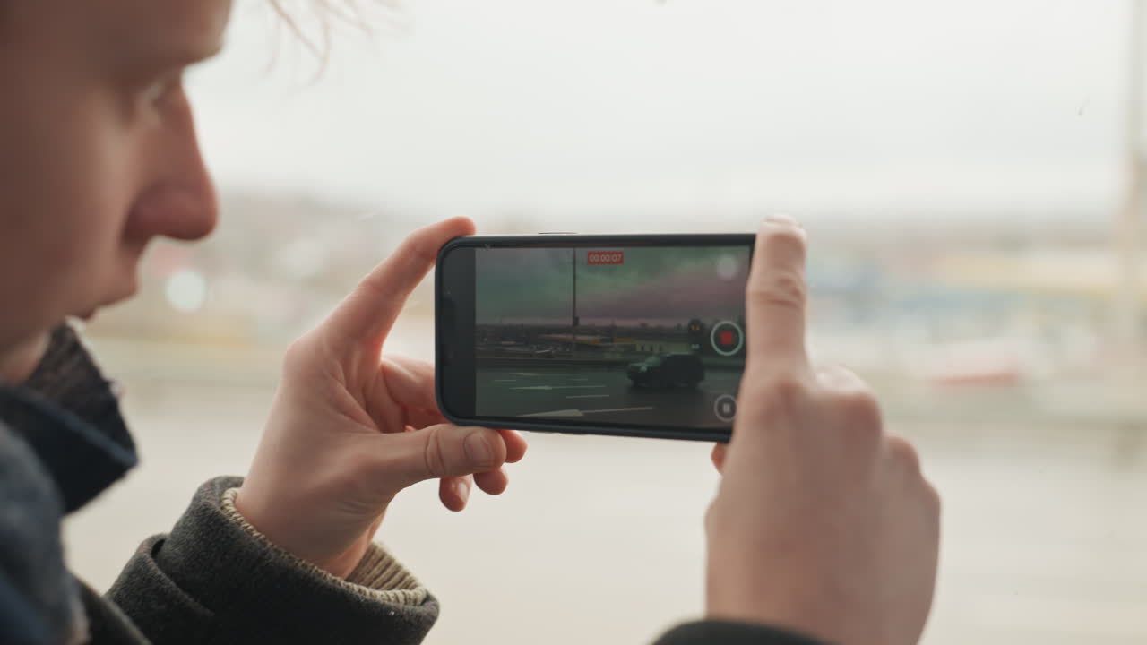 Individuo concentrado en un juego móvil mientras viaja. Persona se concentra intensamente en el teléfono mientras la ciudad pasa. Usuario interactúa con el juego en dispositivo móvil mientras se desplaza por el entorno urbano.