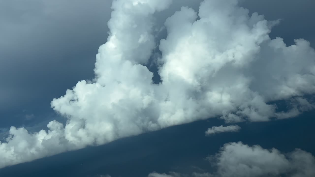 Pilot’s POV FPV flying through a stormy sky full of storm grey color clouds and some white towering cumulus. Aerial footage taken from a jet cockpit. 4K 60FPS