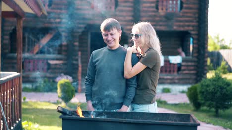 Travelling-Young-guy-with-girl-standing-near-the-barbecue-in-which-coals-are-smoking