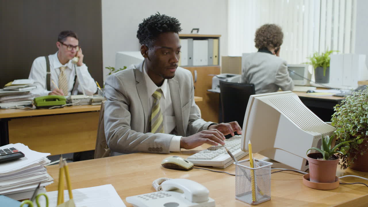 African american businessman working sitting at desk and talking on the phone in a vintage office.