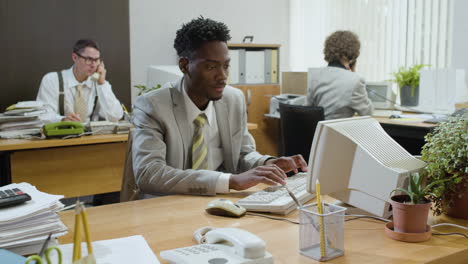 african american businessman working sitting at desk and talking on the phone in a vintage office.