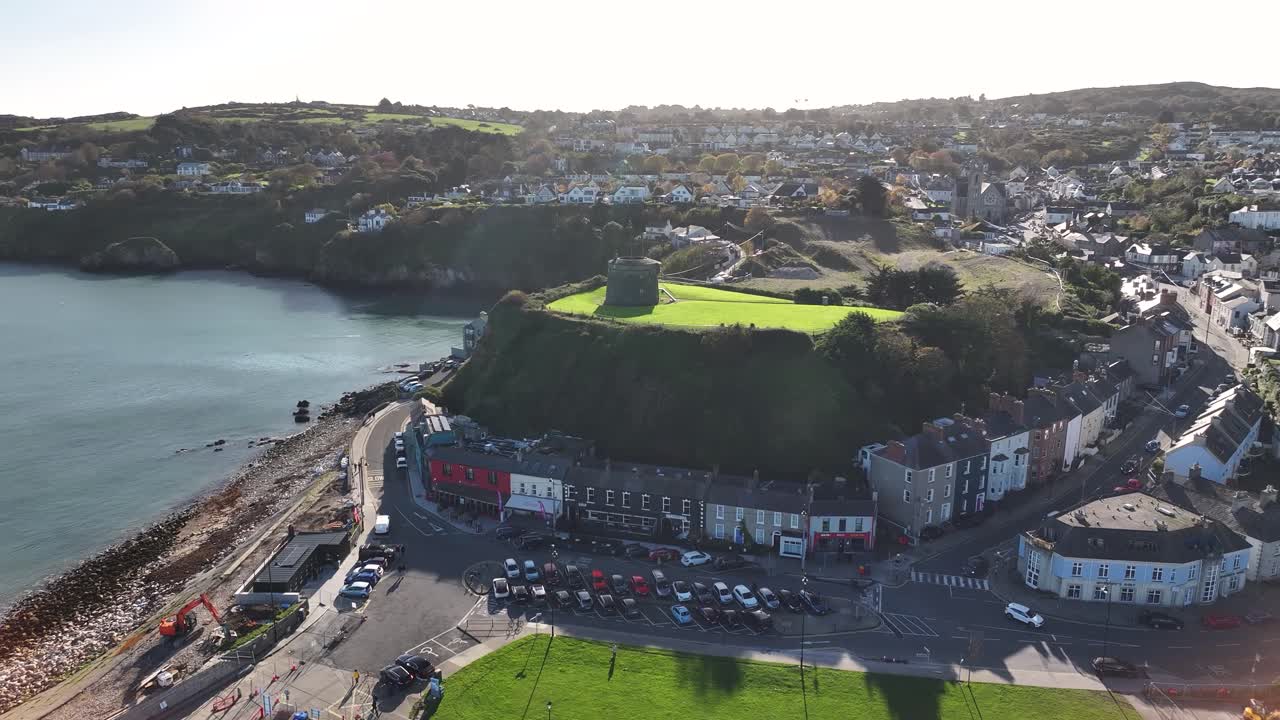 Dinamica ripresa aerea di una piccola torre nella città di Howth, porto turistico, scena costiera. Irlanda, giornata di sole