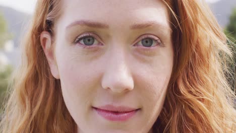 close up video portrait of happy caucasian woman with red hair smiling to camera outdoors