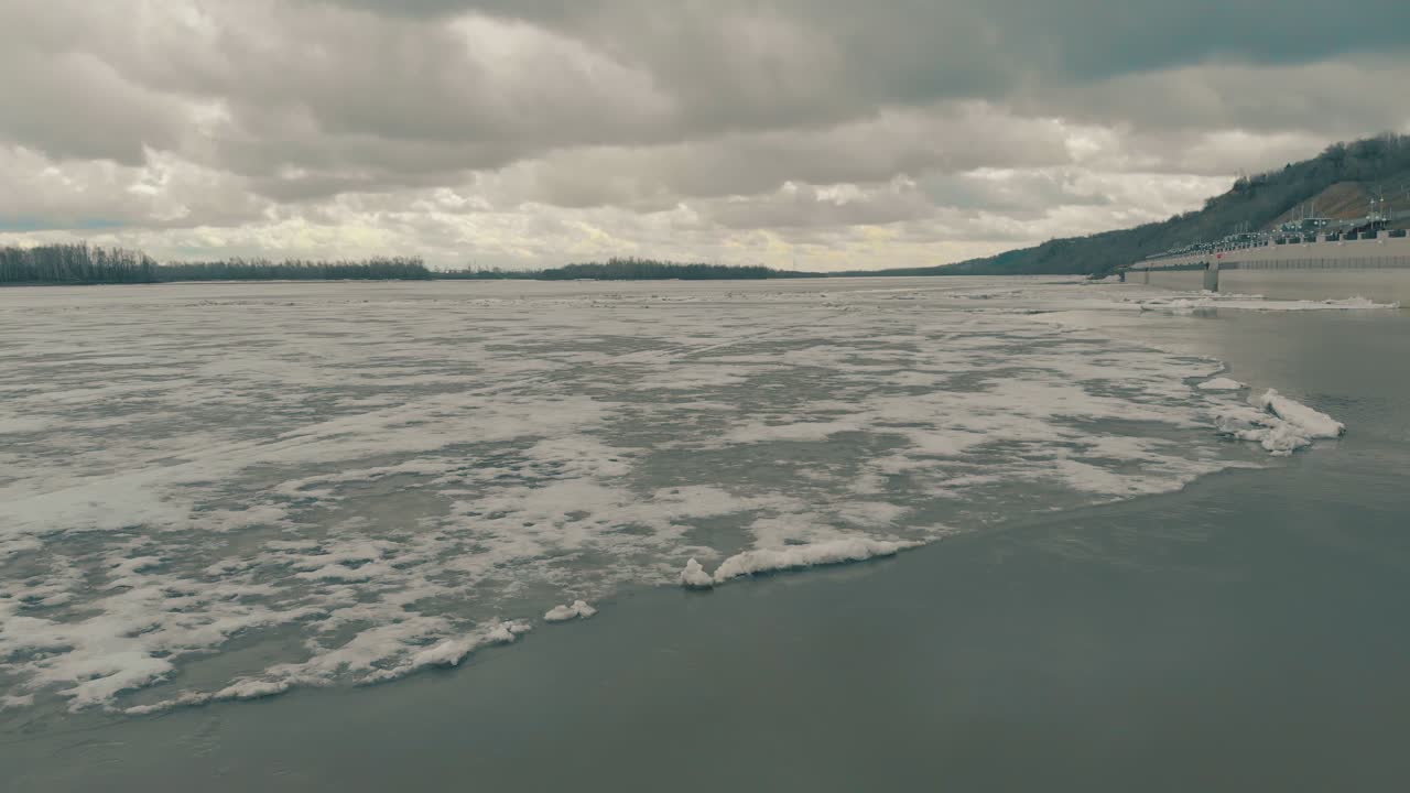 울창한 소나무 숲이 있는 언덕을 배경으로 넓게 얼어붙은 강