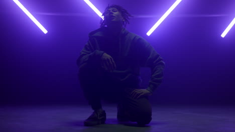 cool dancer guy sitting posing confidently on dance floor in night club lights.