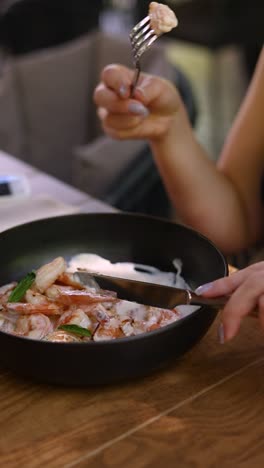 mujer comiendo un plato de pasta de camarón