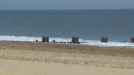 wide shot of the waves crashing over the sea defence groynes at walcott beach