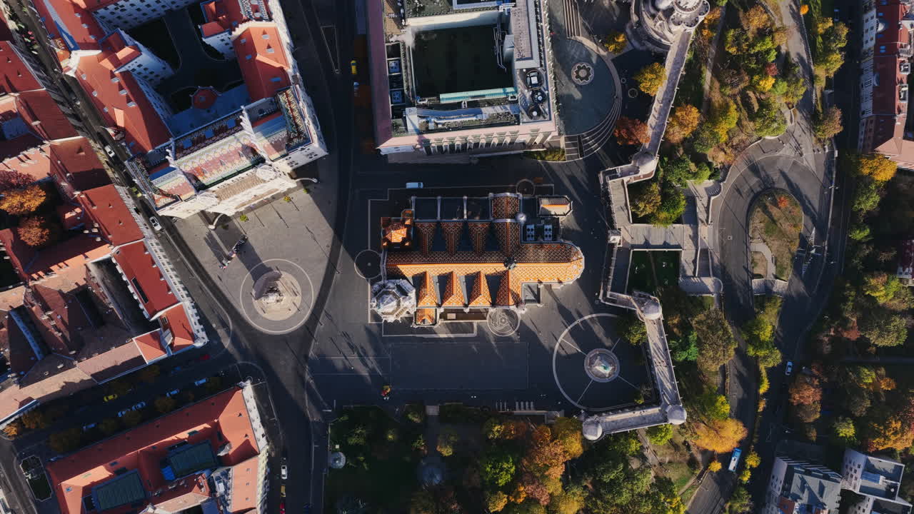 A perfect top-down aerial of Matthias Church reveals its patterned roof, geometric square, and Fisherman’s Bastion’s circular towers