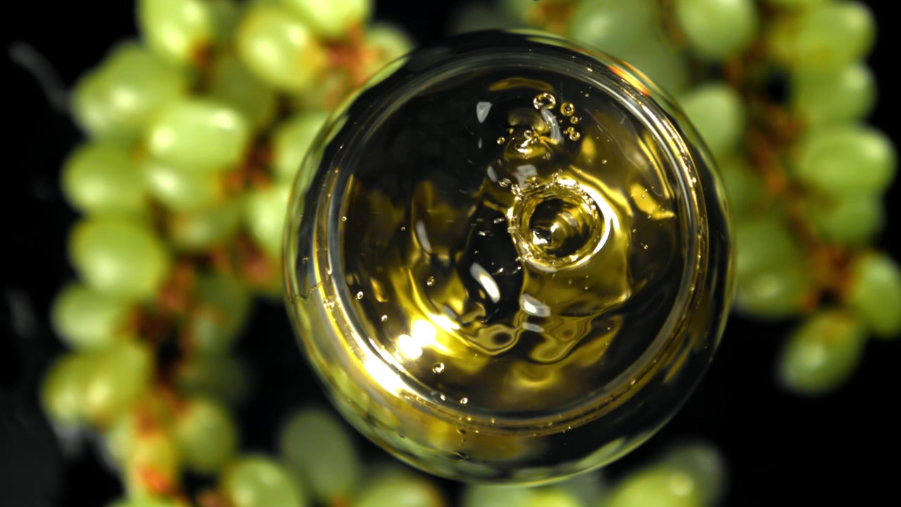 Gocce in super slow motion che schizzano in un bicchiere di vino bianco con uva verde