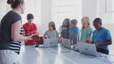 Estudiantes-Con-Profesor-En-Clase-De-Codificación-Informática-Después-De-La-Escuela-Aprendiendo-A-Programar-Vehículos-Robot