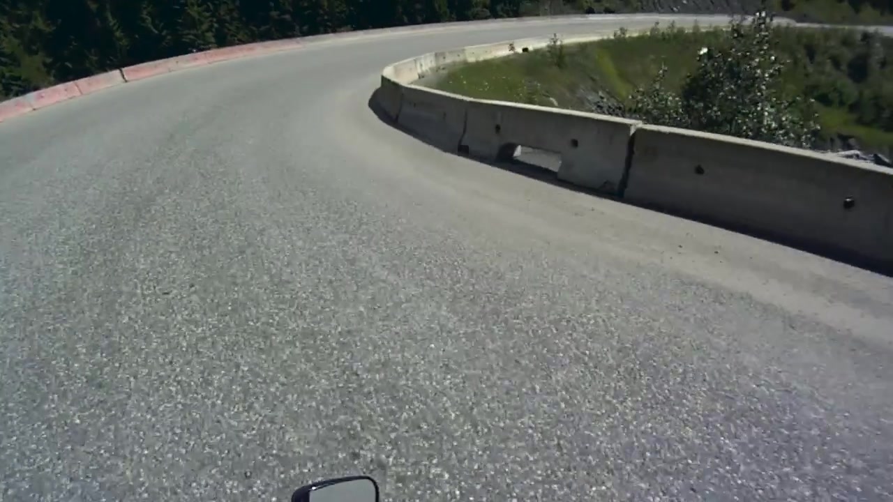 Clip POV di un motociclista su una tortuosa strada forestale di montagna in estate.