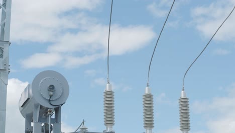 many high voltage electrical insulators in power substation against blue sky background