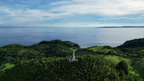 Aerial-view-of-Bote-Lighthouse-atop-a-tree-covered-hill-in-Catanduanes,-a-beautiful-Philippine-island