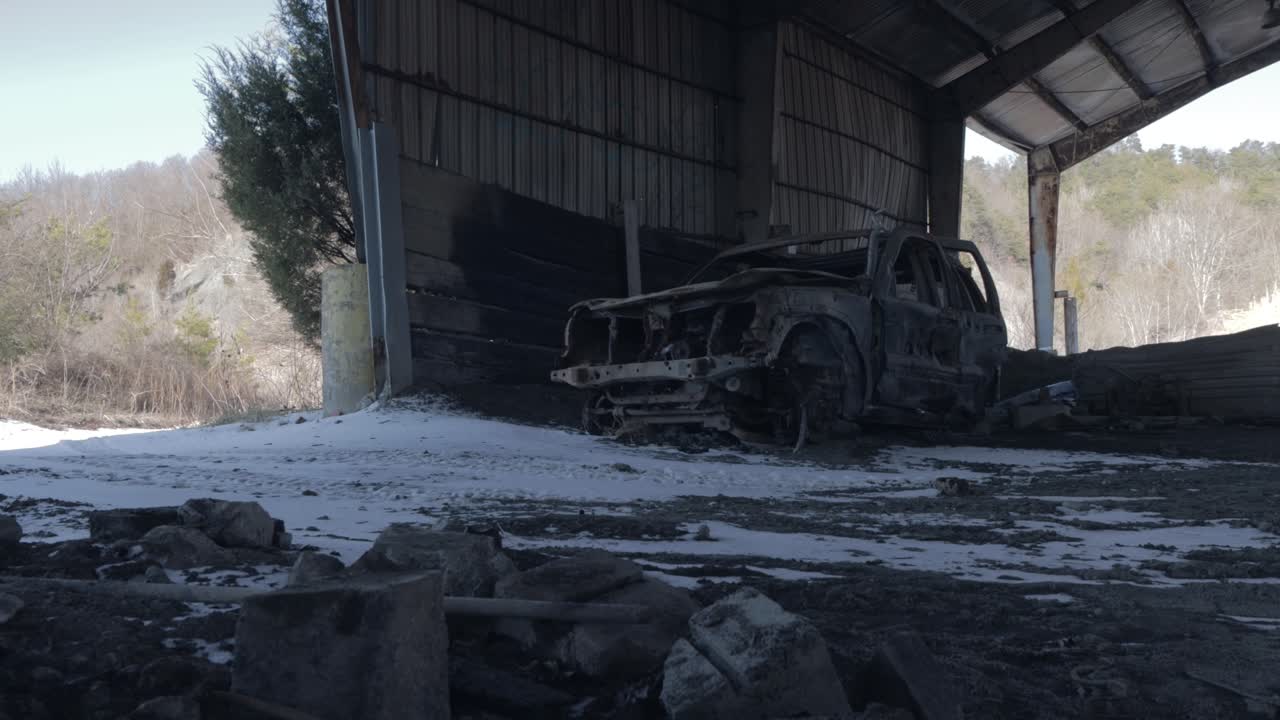 눈이 내리는 겨울 동안 버려진 건물에서 소름 끼치는 파손된 자동차의 슬라이더 영상