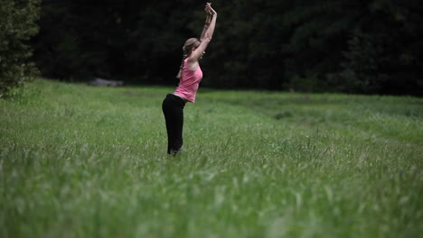 a young woman does yoga exercises in a field of grass