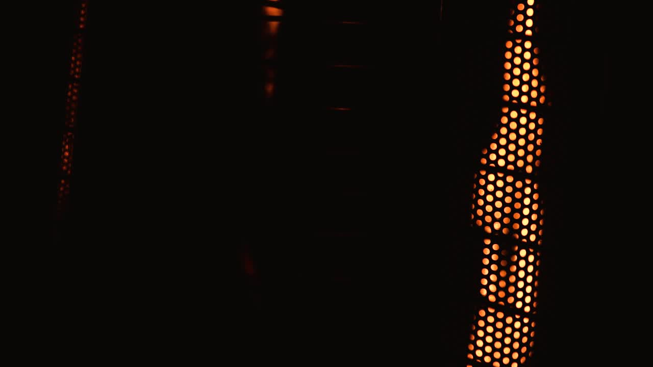 una llama parpadeante se esconde detrás de una rejilla de metal mientras emite un cálido resplandor.