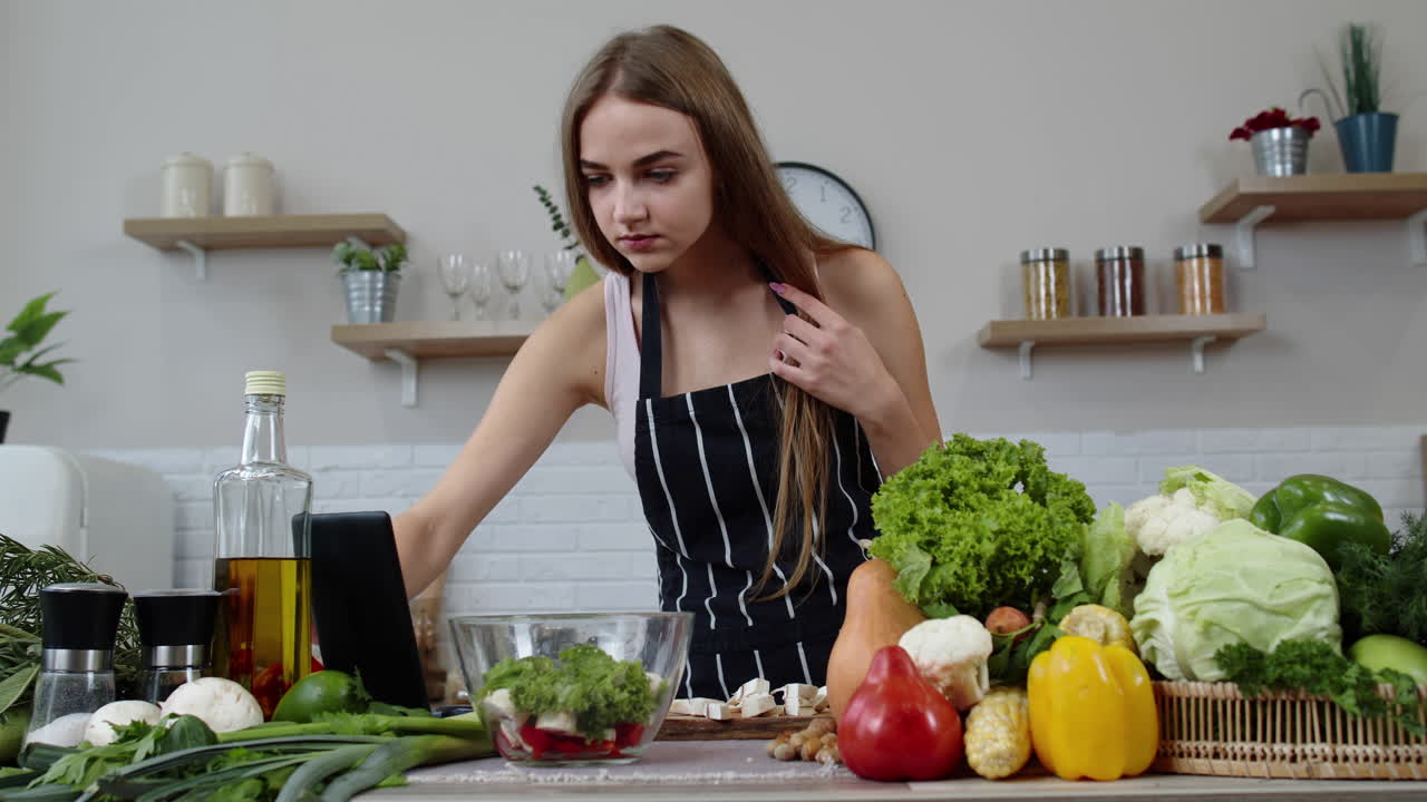 donna vegana alla ricerca di ricette culinarie online su tablet digitali. cucina insalata con verdure crude