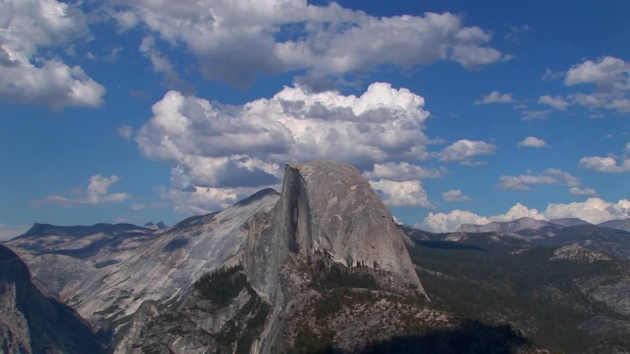 un lapso de tiempo de nubes blancas sobre un cielo azul y una cordillera rocosa en el parque nacional de yosemite california