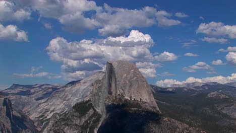 un lapso de tiempo de nubes blancas sobre un cielo azul y una cordillera rocosa en el parque nacional de yosemite california