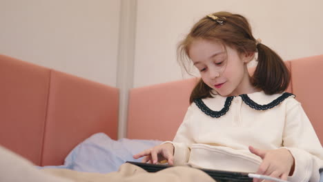 young girl using tablet on bed