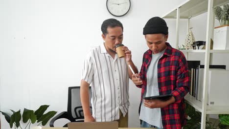 two young asian male entrepreneur discussing sales report on tablet
