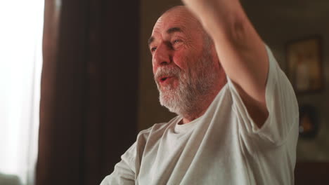 Elderly Man Raising Arm in Home