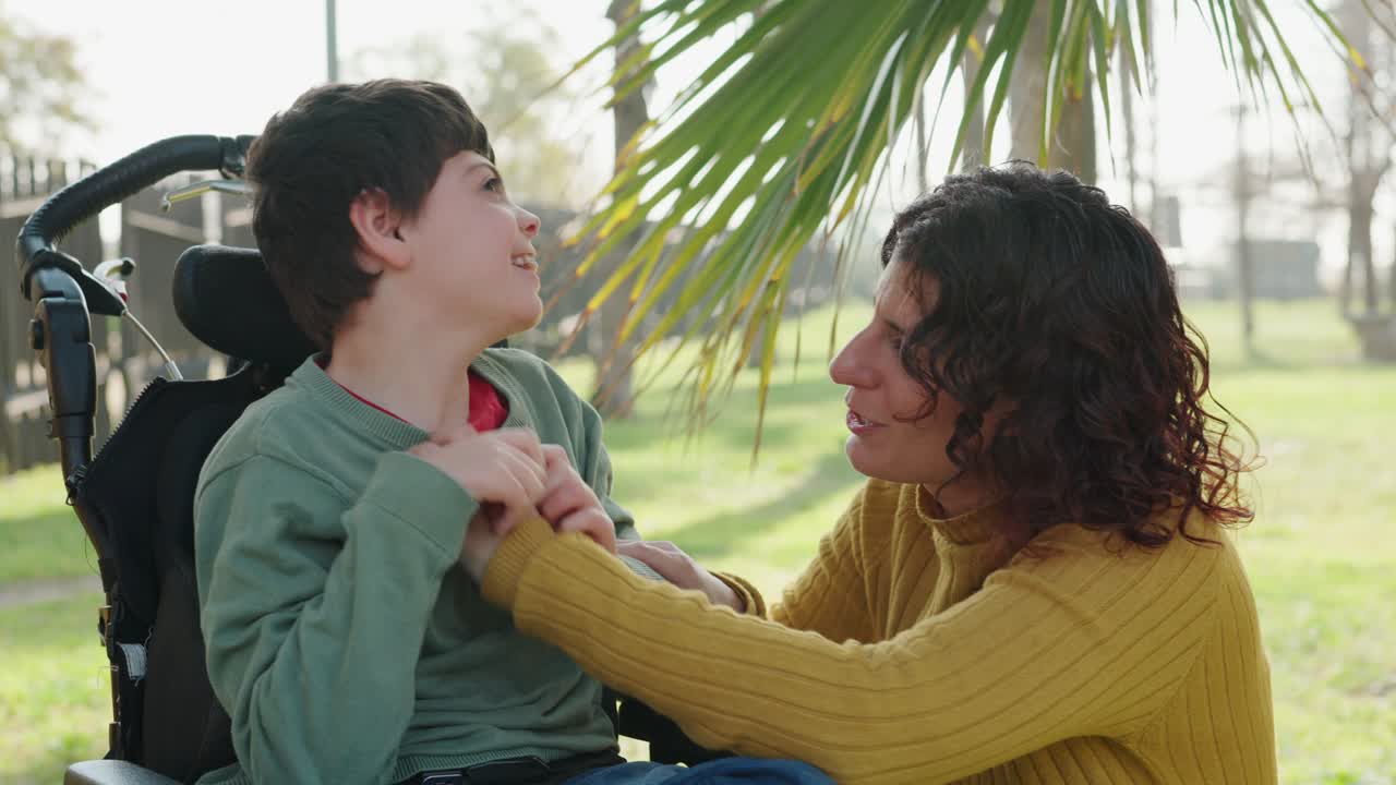 Mother and son in wheelchair interacting in the park