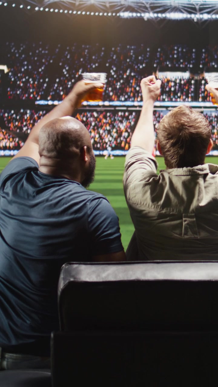 Video vertical. Hinchas de fútbol ven la transmisión del partido en casa creando ambiente de estadio
