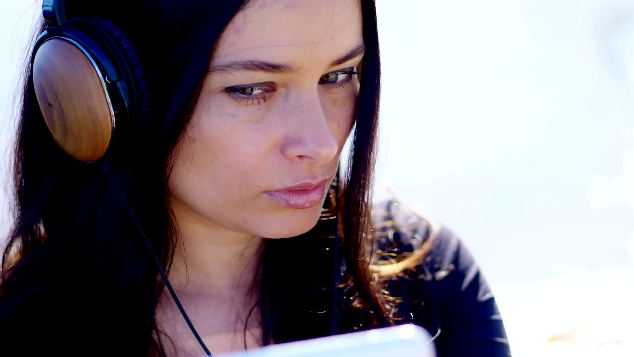 verano, al aire libre, retrato de una mujer hermosa, con cabello largo y oscuro, escuchando música en auriculares de un teléfono móvil, dispositivo, se retira en el teléfono, hace selfies