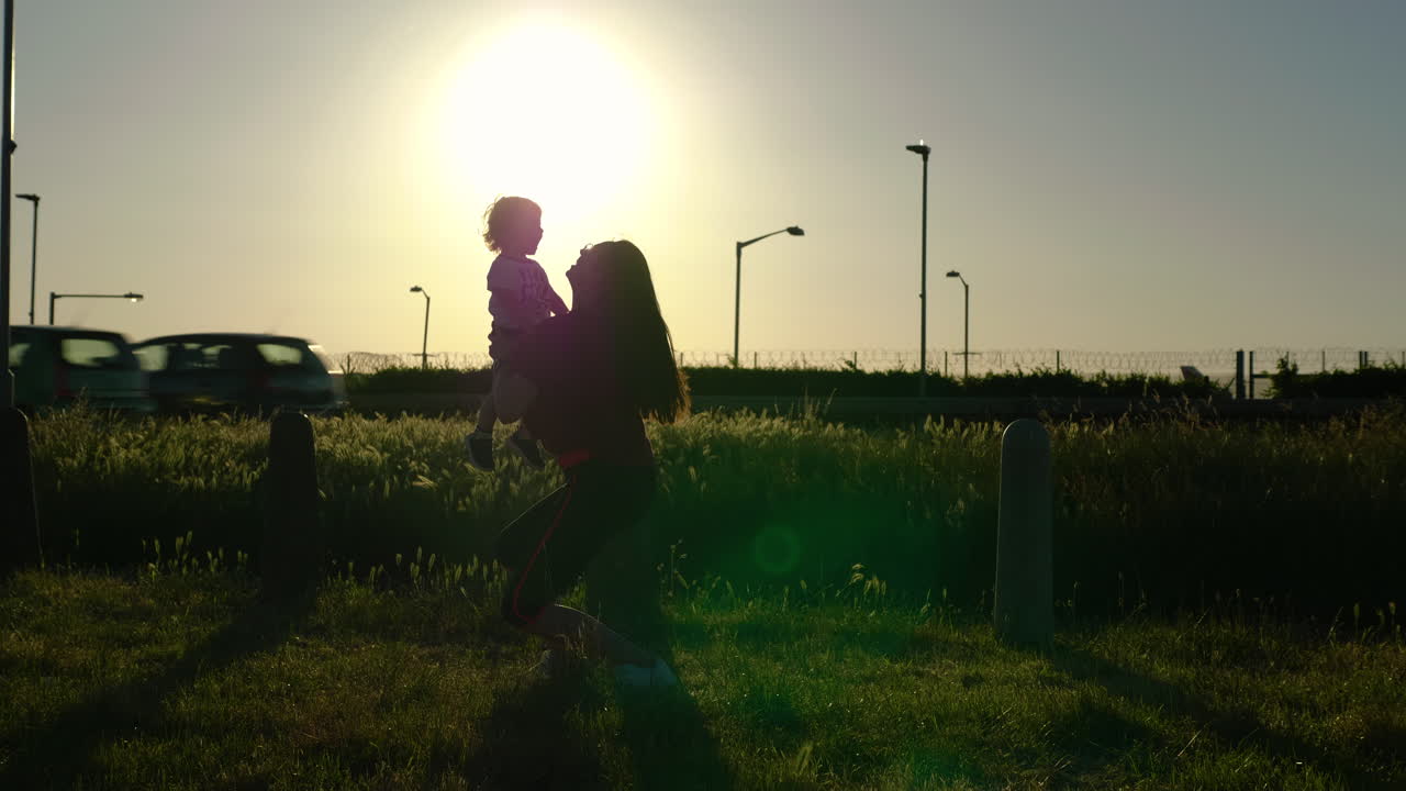 Mom and toddler playing catch in gorgeous sunset light with big sun in background