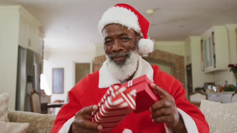 portrait of happy senior african american man at christmas time wearing santa costume