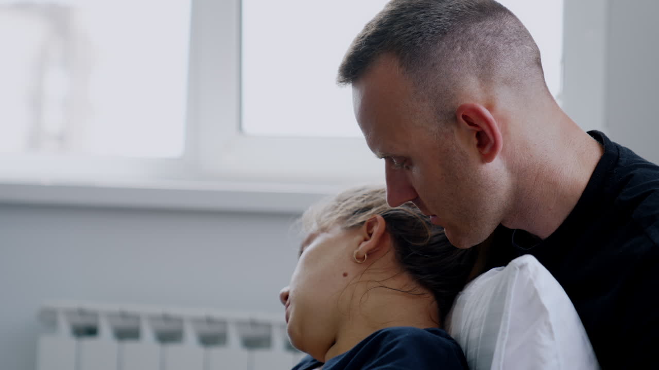 Woman sits her back to a man. Husband talks to his wife feeling bad from contractions. Close up.