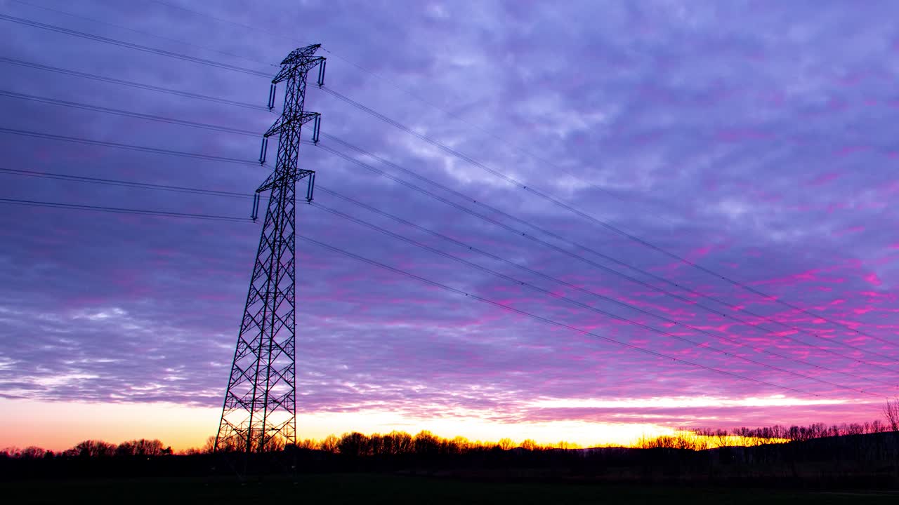 Time lapse of an electricity pole during a cloudy red purple sunset