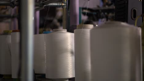 trabajo de fabricación de máquinas calcetines medias - primer plano de bobinas con hilo blanco en el vídeo de la máquina de rebobinado