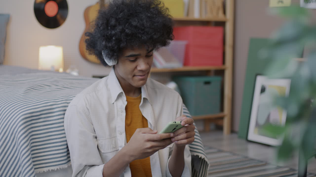 Teenager Listening to Music and Using Smartphone in Bedroom