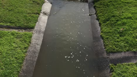 El-Agua-De-Lluvia-Que-Fluye-En-Una-Alcantarilla-Bajo-Un-Tubo-De-Desagüe-Durante-El-Día-En-Auckland,-Nueva-Zelanda