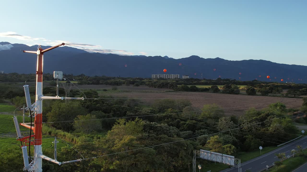 Lateral drone cable movement revealing a large electricity transmission tower with a highway visible in the background
